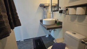 Un bagno moderno con un lavandino bianco, un water, un porta asciugamani e uno specchio.