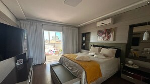 Et moderne hotelværelse med seng, fjernsyn, skrivebord og udsigt ud i det fri.