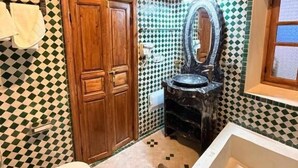 Un baño con suelo de baldosas a cuadros, puerta de madera, espejo y bañera.