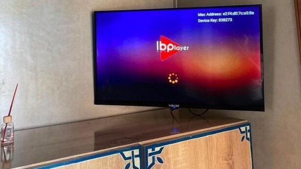 Un televisor montado en la pared con un mueble de madera debajo.