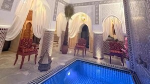 Un área de piscina interior lujosa, con arquitectura ornamentada que incluye arcos y suelo de baldosas.