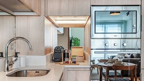 A modern kitchen with a built-in oven, a sink, and a dining area with a table and chairs. - Nest Collection El Golf (Las Condes)