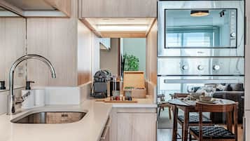 A modern kitchen with a built-in oven, a sink, and a dining area with a table and chairs.