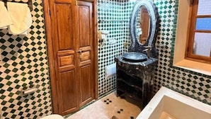 Un baño con suelo de baldosas a cuadros, puerta de madera, espejo y bañera.