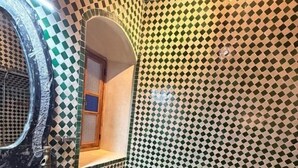 Un baño con piso de baldosas a cuadros, un espejo redondo y una bañera.