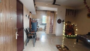 A room with a bed, a dining area with chairs, a ceiling fan, and a decorative wall.
