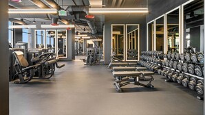 Une salle de sport équipée de matériel d’exercice, d’haltères et dotée d’une grande fenêtre.