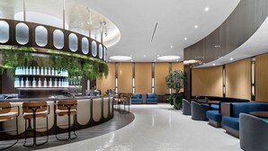 Un espace bar moderne doté d’un comptoir incurvé, de tabourets de bar et d’un coin salon avec des canapés et des fauteuils.