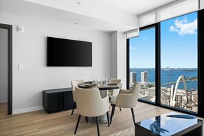 A modern dining area with a round table, chairs, and a large window offering a view of a cityscape and water. - Downtown Miami Condo w/ Rooftop Pool & Valet (Miami)