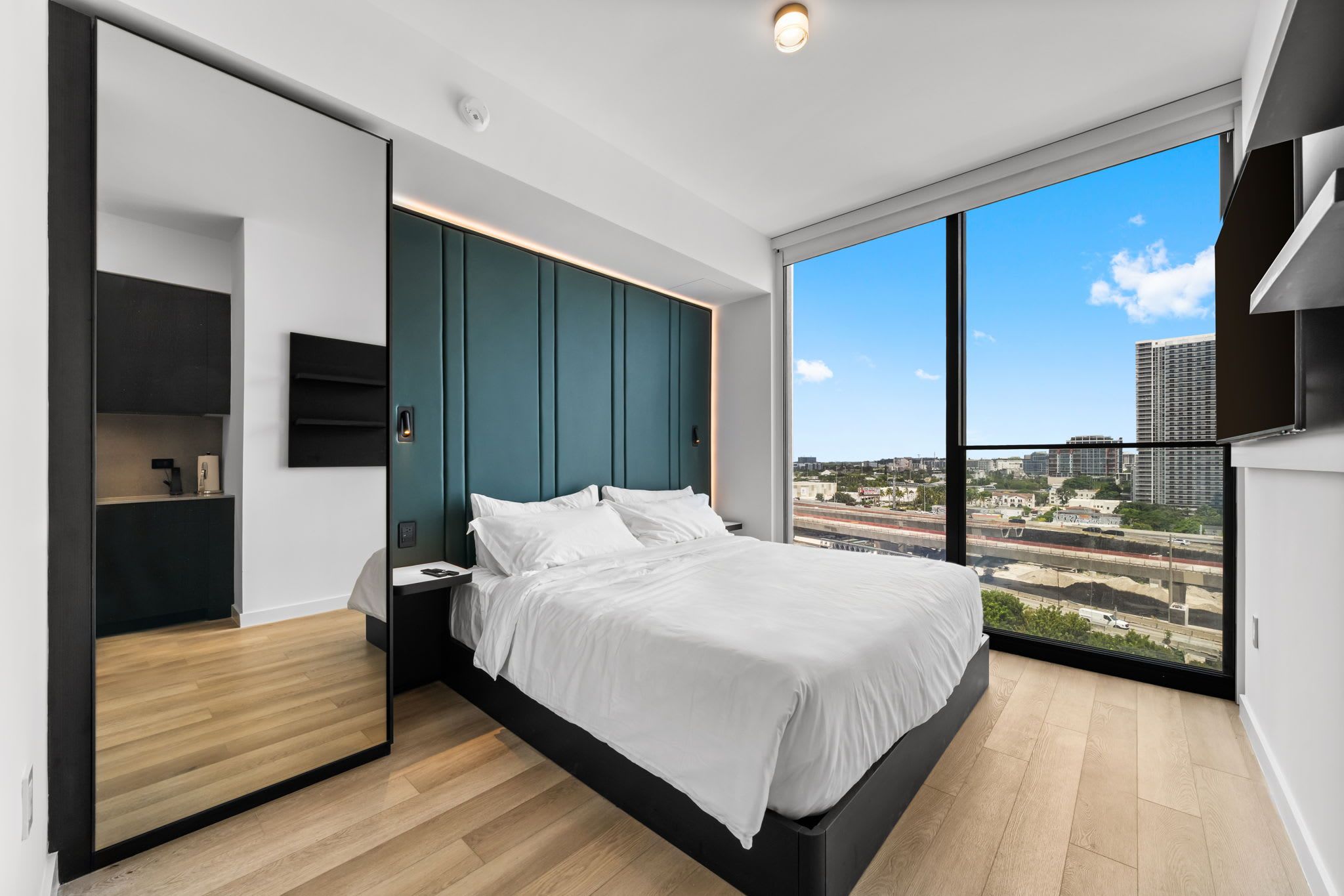 Un dormitorio moderno con una cama grande, armario empotrado y vistas a la ciudad.