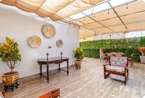 An indoor space with a wooden floor, a table, a chair, and a wall with a green plant wall.