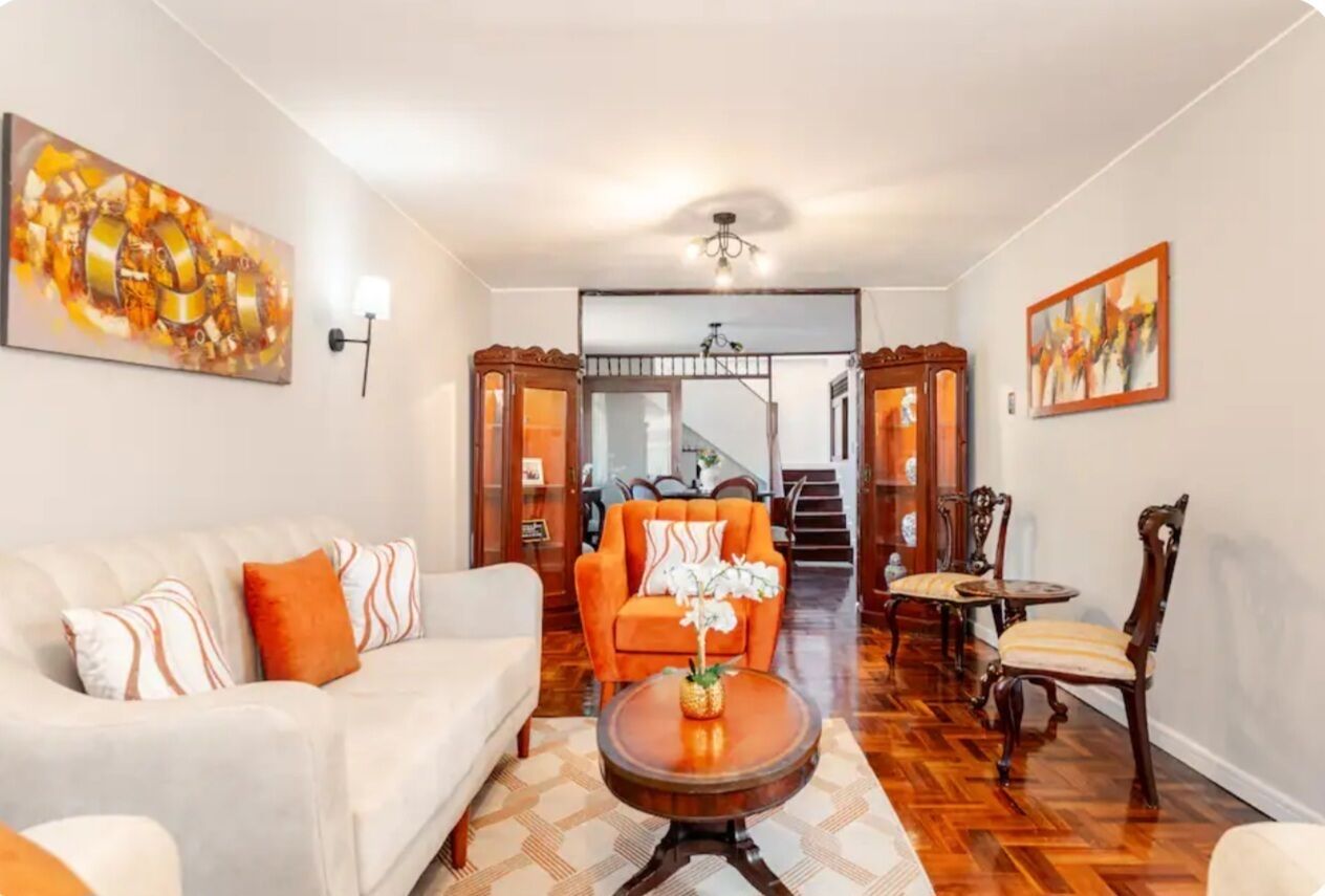 A living room with a sofa, armchair, coffee table, and a staircase leading to another level.