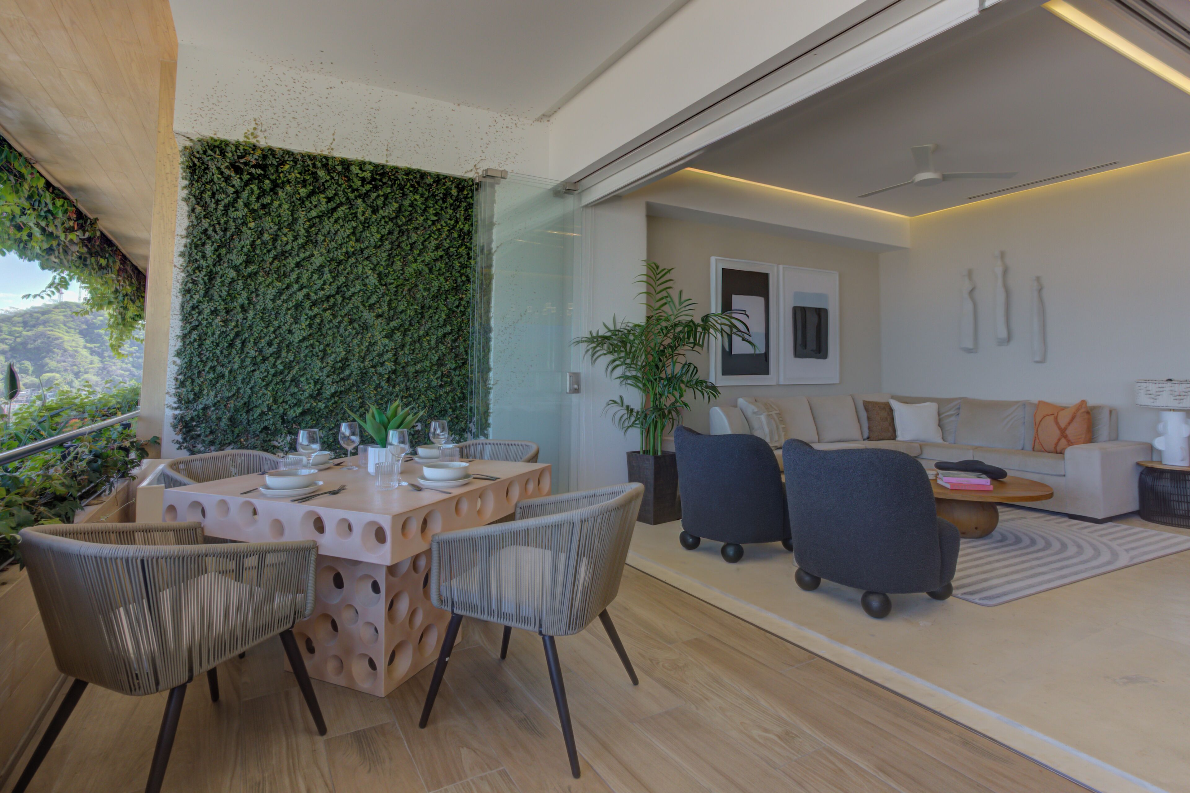 Un intérieur moderne comprenant un coin repas, un canapé et un mur végétal.