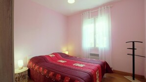 A bedroom with a bed, a bedside table, a lamp, a window with curtains, and a radiator. - Le Pin Franc - VALEYRAC (VALEYRAC)