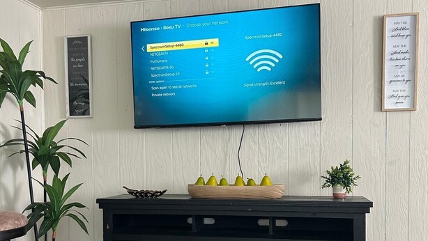Een flatscreen-tv aan de muur, met zenders selectie op het scherm.