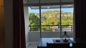 A room with a balcony overlooking a hillside with buildings. - Spacious, cool, and tastefully decorated one bedroom with pull out sofa. (Kingston)