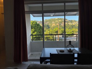 Ein Zimmer mit Balkon und Blick auf eine Hügellandschaft mit Gebäuden.