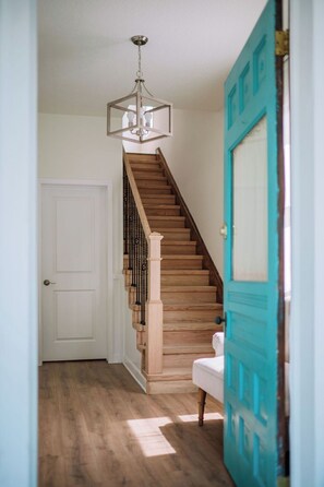 A staircase with wooden steps and black balusters, leading to a white door. - Stay Downtown St. Augustine 3BR and Parking (St. Augustine)