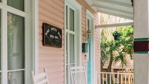 Eine Veranda mit zwei Schaukelstühlen, einem Deckenventilator und einem Schild mit der Aufschrift 'Home Sweet Home'.