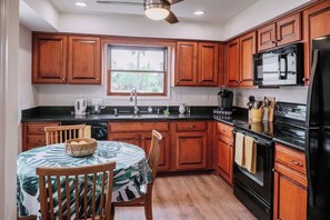 A kitchen with wooden cabinets, a black refrigerator, a microwave, and a stove. - Stay Downtown St. Augustine 3BR and Parking (St. Augustine)