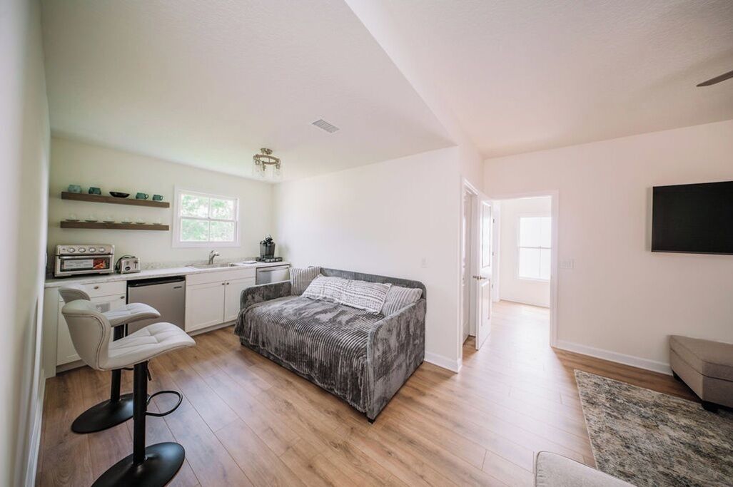 Een moderne kamer met een bed, een barkruk, een kitchenette en een aan de muur bevestigde televisie.