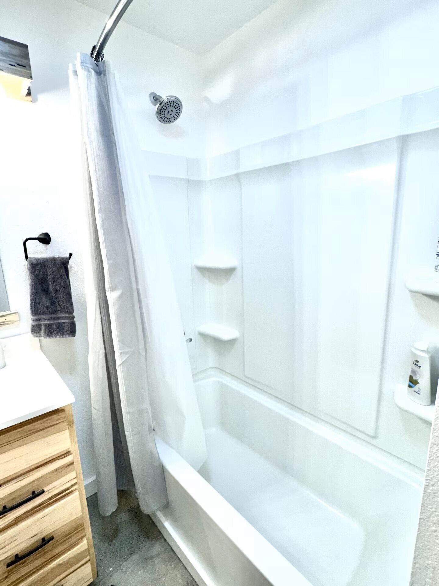 A modern bathroom with a shower, a towel rack, and a soap dispenser.