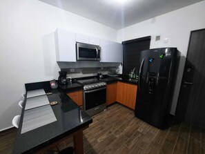 Una cucina compatta con forno a microonde, fornelli e frigorifero.