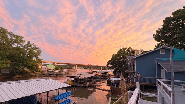 A waterfront dock area with boats, a covered seating area, and a building with a balcony.