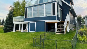 A modern two-story house with a large glass window, a covered porch, and a staircase leading to the upper level.