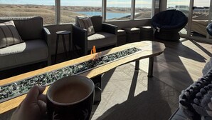A modern interior with large windows, a sofa, a chair, a coffee table, and a view of a landscape.