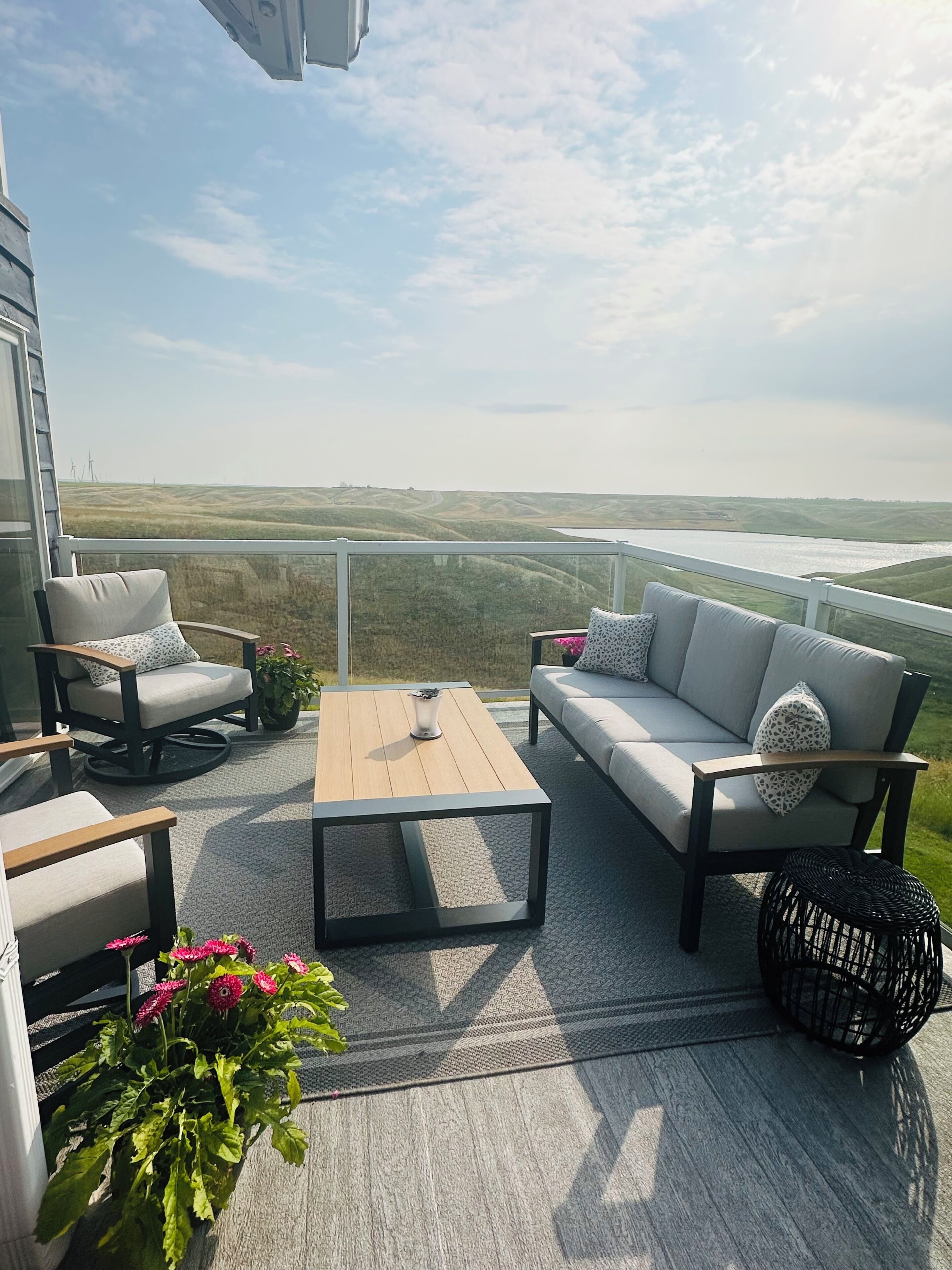 Un balcon aménagé avec un canapé, des fauteuils, une table basse et une vue sur la campagne.