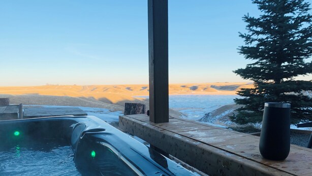 A hot tub with a view of a snowy landscape and a tree.