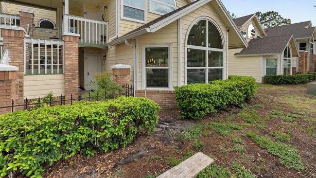 Une maison à deux étages avec un porche à l’avant, un garage et un jardin bien entretenu.