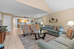A living room with a sofa, armchairs, a coffee table, and a kitchen in the background. - Laguna Bay Family Vacation Retreat (Kissimmee)