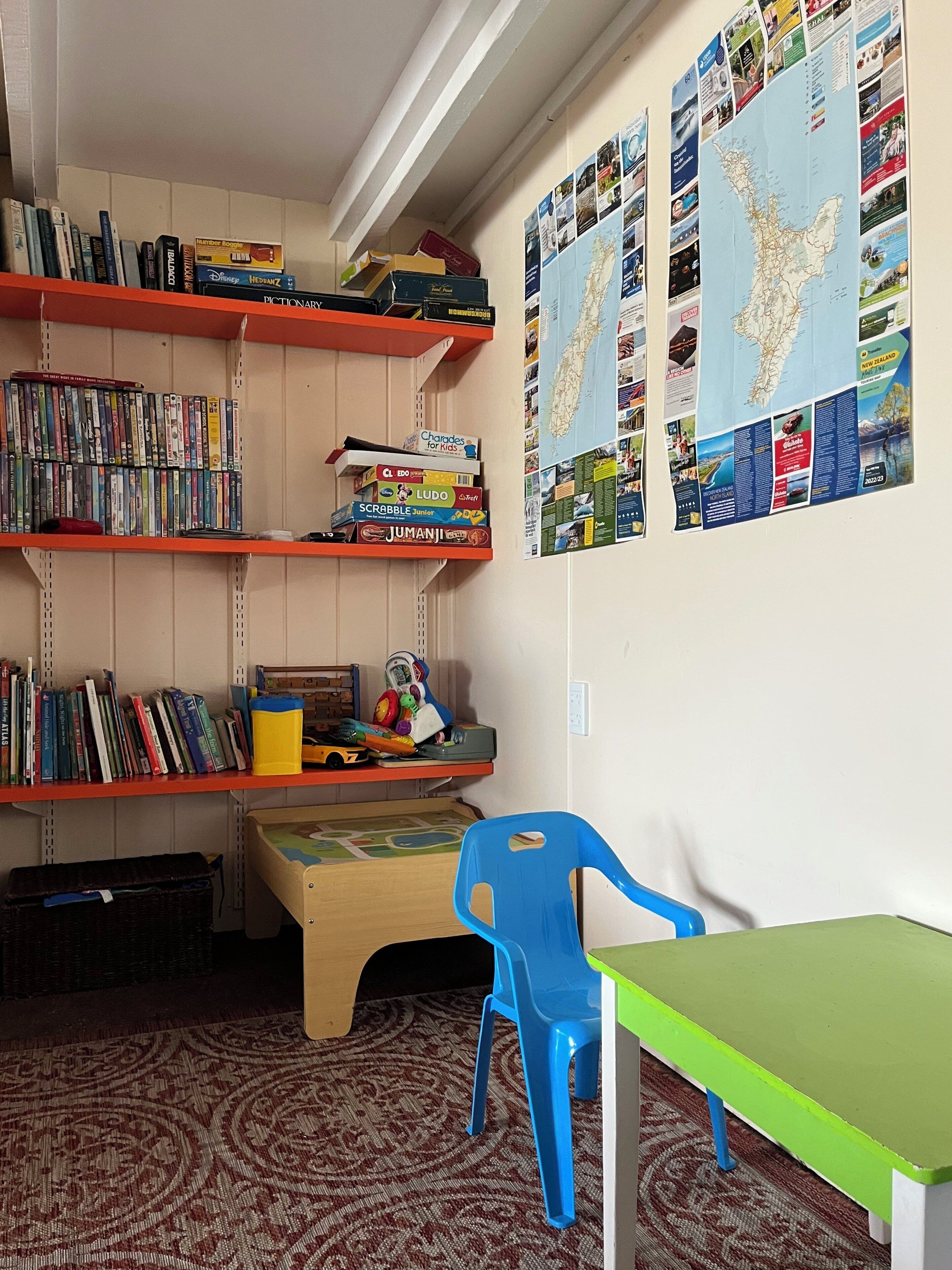 Une pièce comprenant une bibliothèque, un bureau, une chaise et des affiches éducatives accrochées au mur.