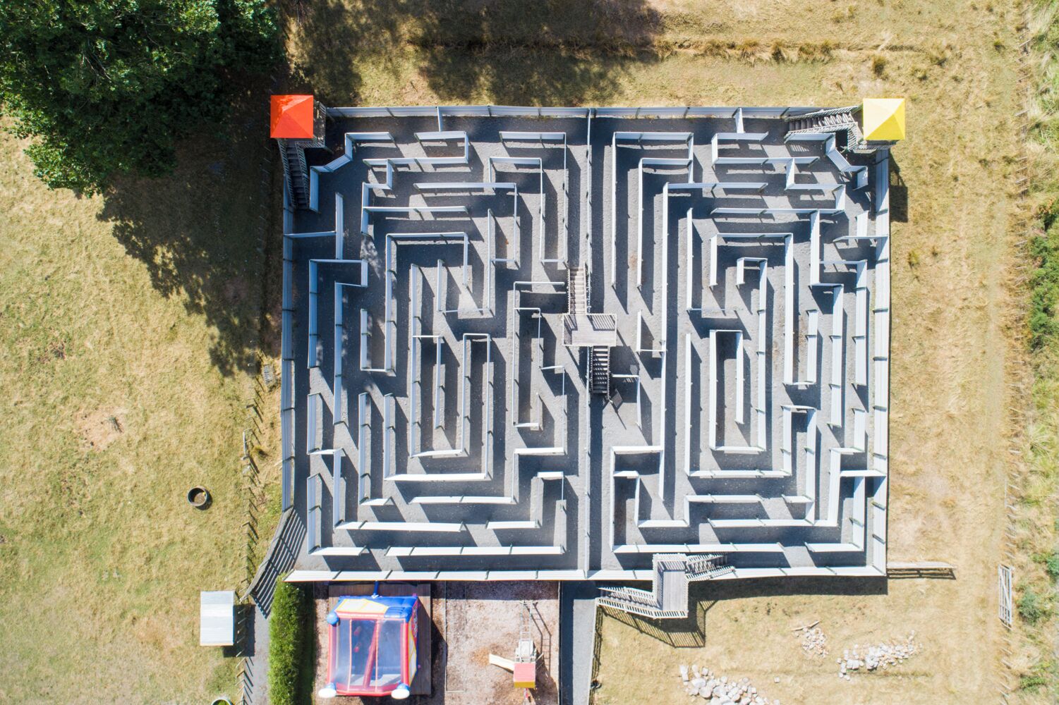 An aerial view of a maze-like structure with a small building at the entrance.