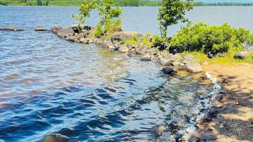 A calm lake with clear water, surrounded by rocks and greenery.