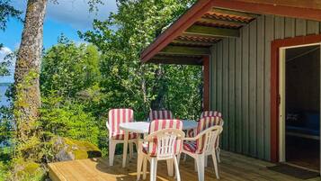 A wooden deck with a table and chairs, a covered seating area, and a view of a lake.
