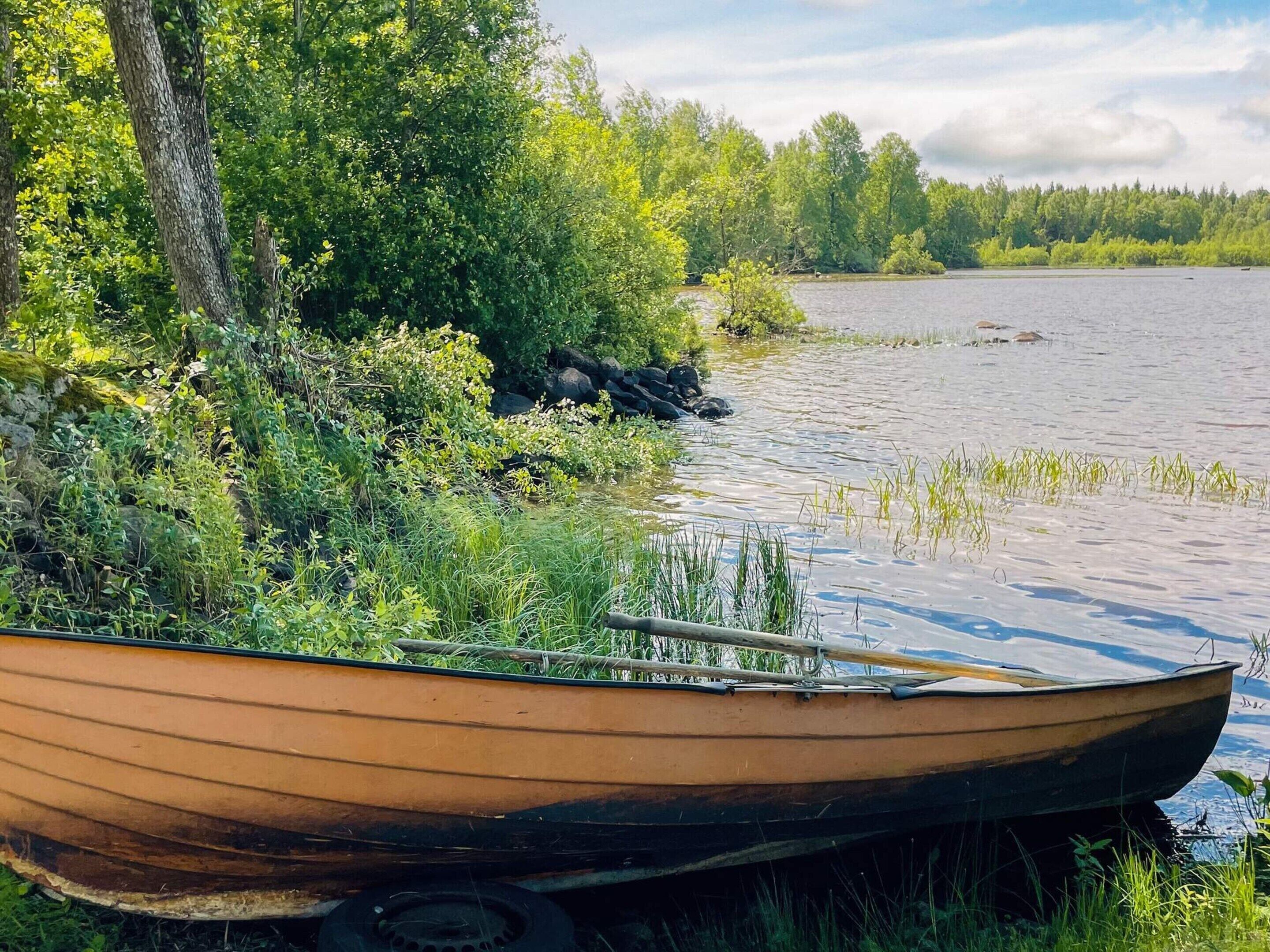 A boat tied to a dock with a forested shoreline and calm water.