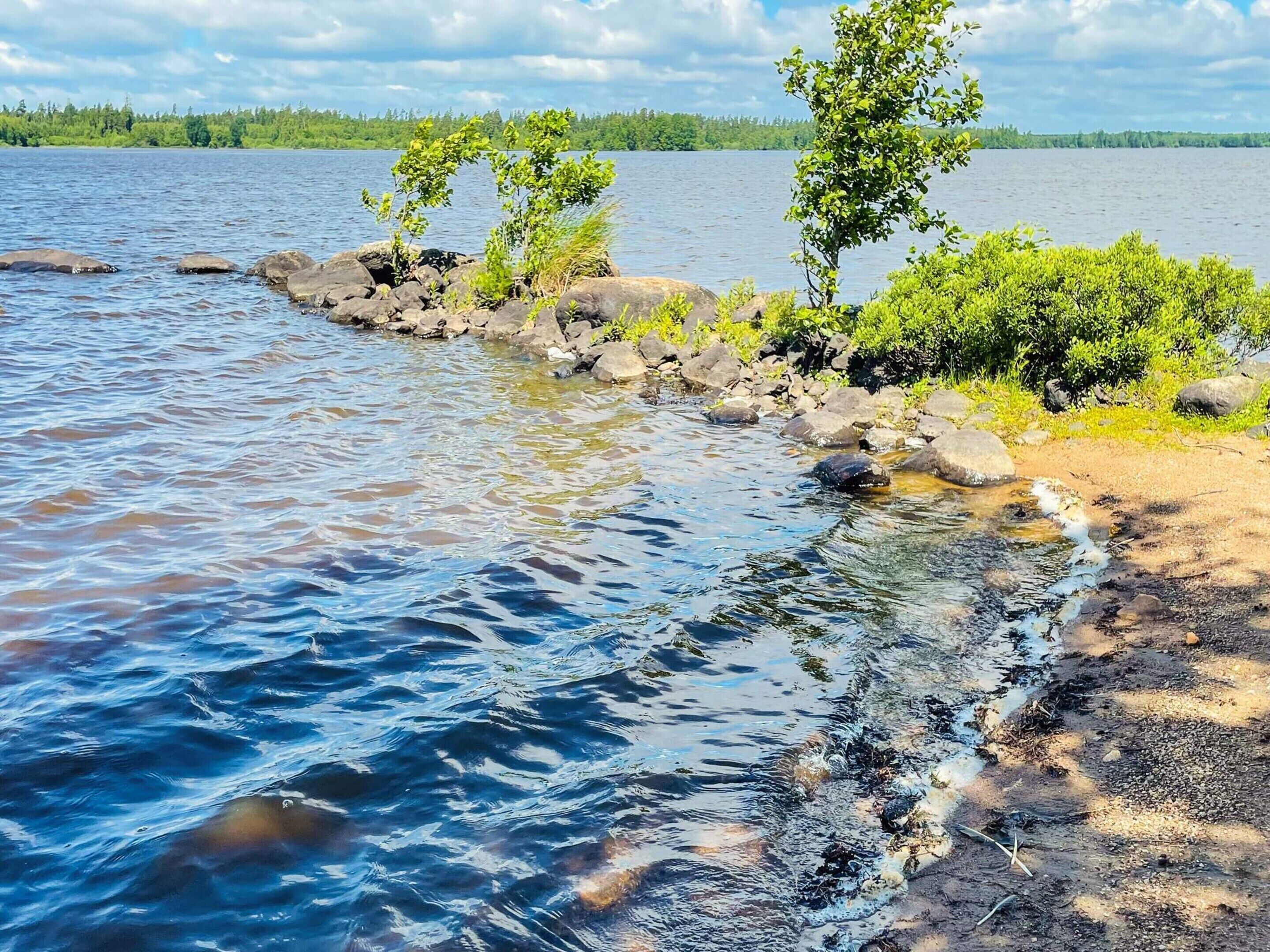 Un lac paisible aux eaux limpides, bordé de rochers et de verdure.
