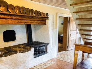 A stone fireplace with a black hearth, a wooden shelf above it, and a wooden staircase to the right. - 9 Person Holiday Home in Almhult (Almhult)