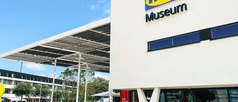 Un musée IKEA doté d’une architecture moderne, avec une entrée imposante et un espace extérieur abrité.