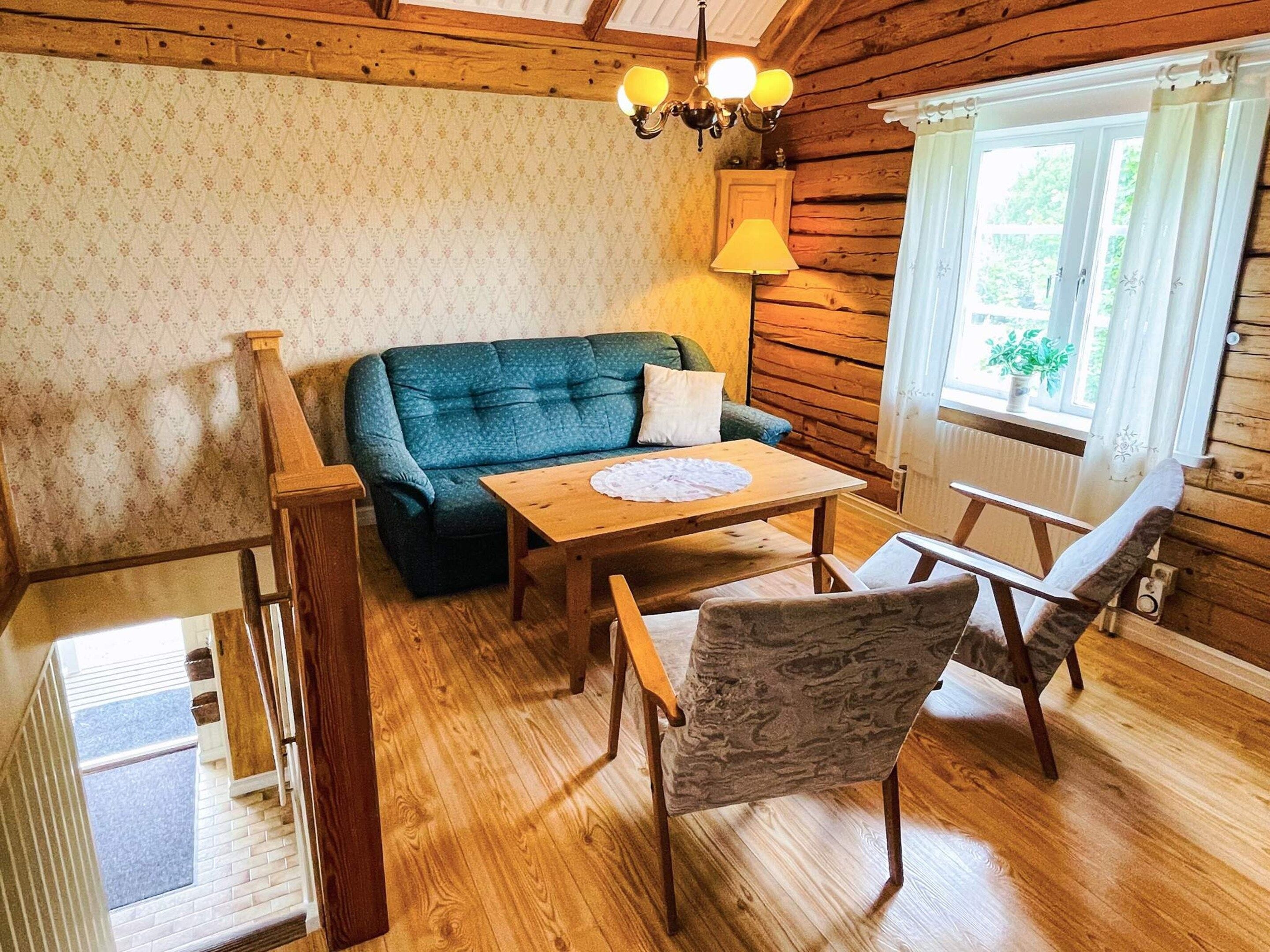 Interior d'una cabana acollidora, amb un sòl de fusta, un sofà verd, una taula de fusta i una cadira.