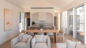 Un interior moderno con comedor, sofás y un ventanal amplio.