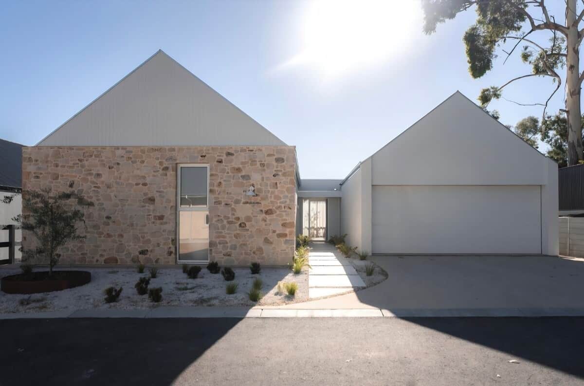 A modern two-story house with a stone facade, a garage, and a clear sky.