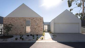 A modern two-story house with a stone facade, a garage, and a clear sky.
