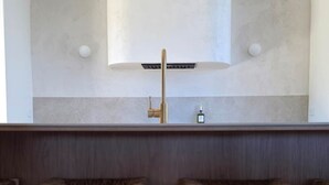 Una cocina con salpicadero blanco, dos taburetes de madera y un grifo moderno.