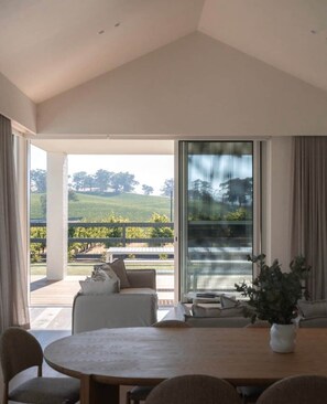 A room with a large sliding glass door leading to an outdoor area with a view of a vineyard.