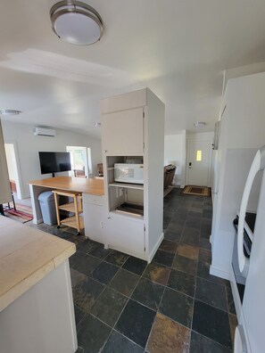 A modern kitchen with a built-in microwave, a wooden table, and a TV.