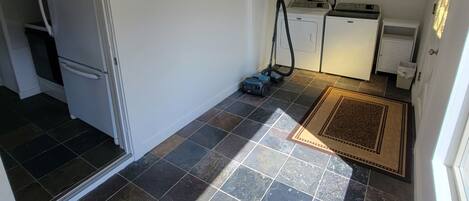 Eine kleine Küche mit Kühlschrank, Waschmaschine und Staubsauger.